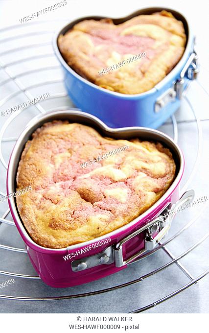 Two heart-shaped cake pans of strawberry pound cake on cooling grid