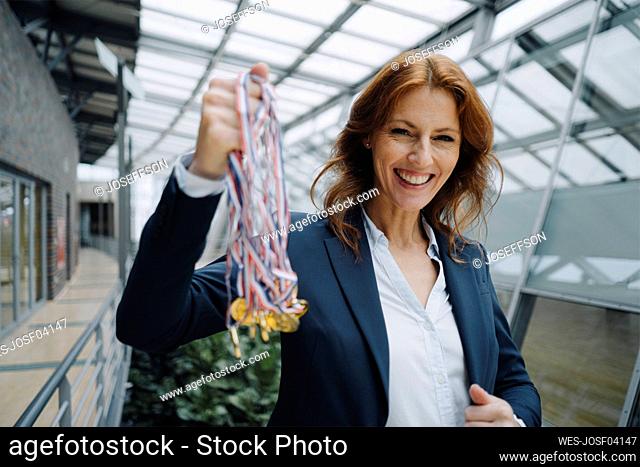 Portait of a happy businesswoman holding medals in office