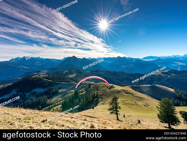 man with paraglider preparing for take off from a high mountain peak in the Swiss Alps on the Chli Aubrig mountain peak