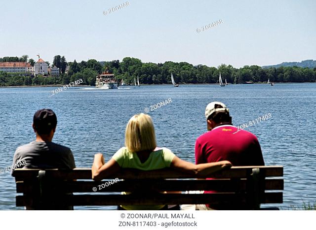 People on a Park Bench Seat over Looking the Chiemsee, Chiemgau Upper Bavaria Germany