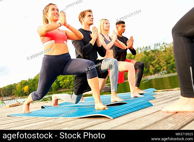 Junge Leute machen eine Übung mit Ausfallschritt im Wellness Yoga Kurs in der Natur