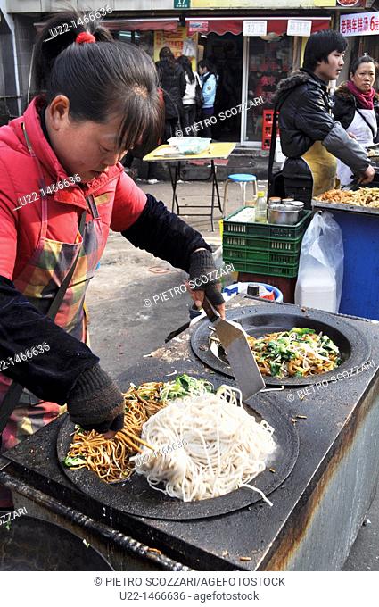 Shanghai (China): a woman cooking noodles in a street market by the Yuyuan Bazaar, in the Old Town