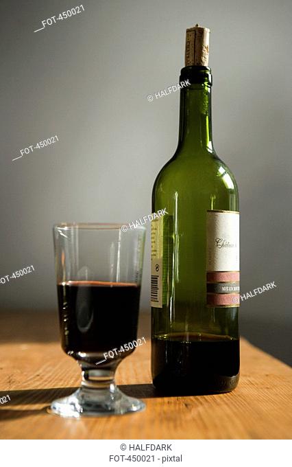 A bottle of red wine and a glass