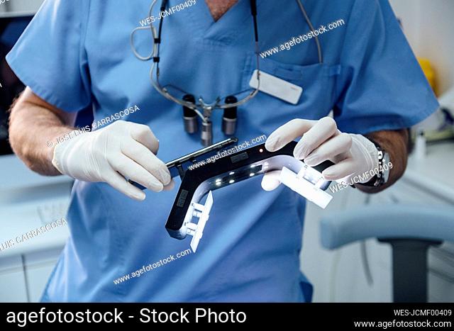 Close-up of dentist holding special photographic apparatus and smartphone