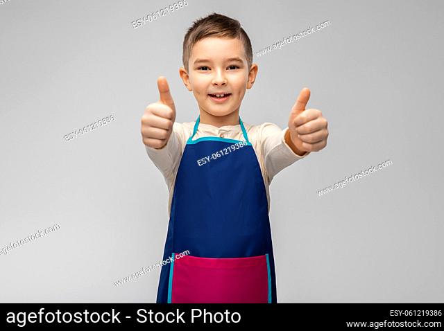 smiling little boy in apron showing thumbs up