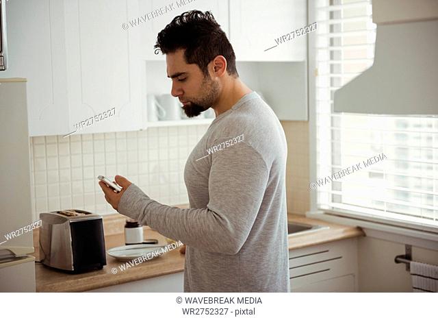 Man using mobile phone in kitchen