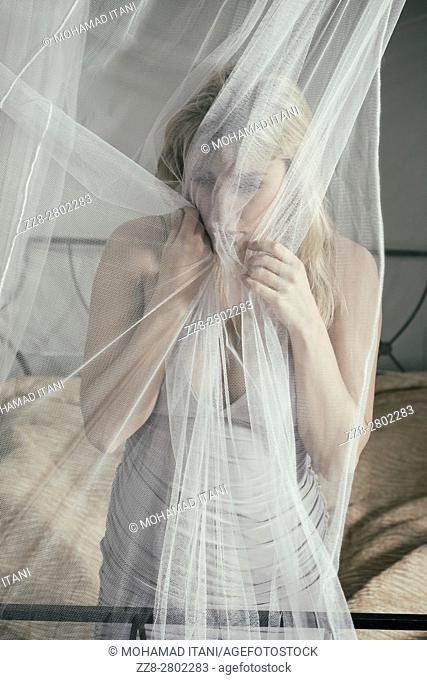 Scared woman grabbing the net on the bed
