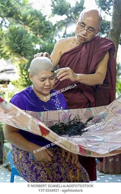 Myanmar (formerly Burma). Mon State. Mawlamyine (Moulmein). Gaungse Kyun, Shampoo island. Monk shaving the head of a young woman during her introduction
