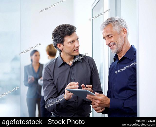 Businessman discussing strategy over tablet PC with smiling mature colleague