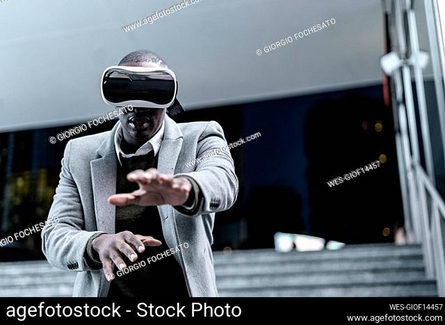 Businessman gesturing wearing virtual reality headset in subway at night