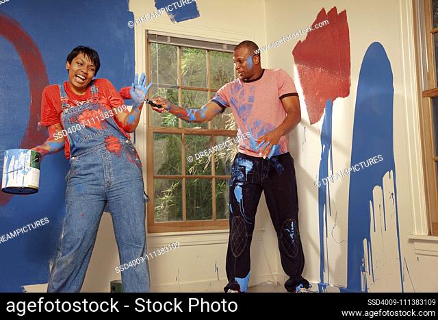 African American couple painting wall and making a mess