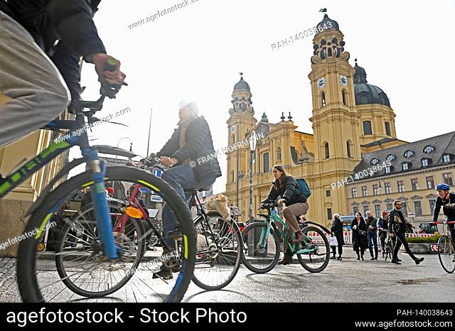 Theme picture winter in the coronavirus pandemic. Hard lockdown. Cyclists and pedestrians on Odeonsplatz in Muenchen with Theatiner Church on February 19th