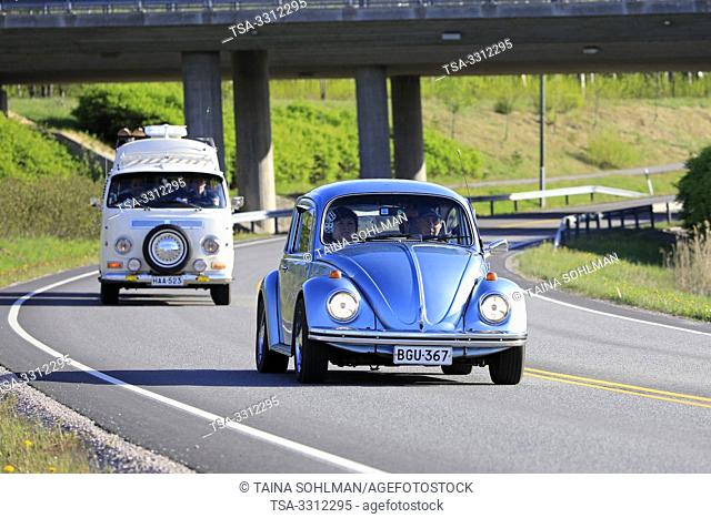 Salo, Finland. May 18, 2019. Classic 1970s Volkswagen Beetle, or Type 1 and white VW camper van, or Type 2 on road on Salon Maisema Cruising 2019