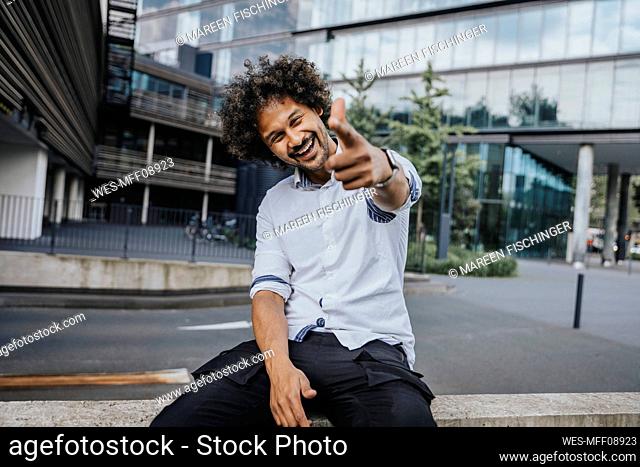 Happy young man gesturing in front of modern building