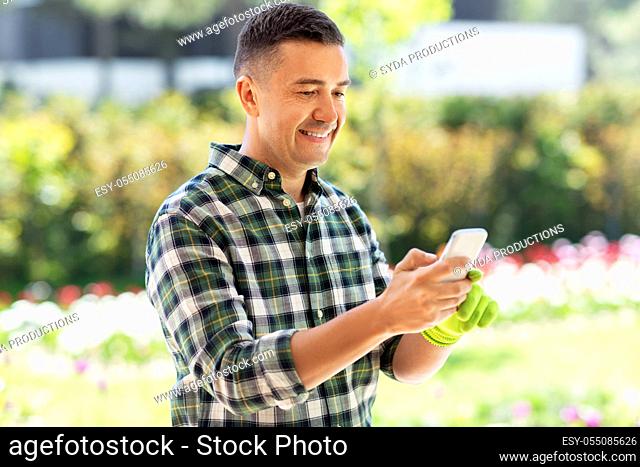 happy man with smartphone at summer garden