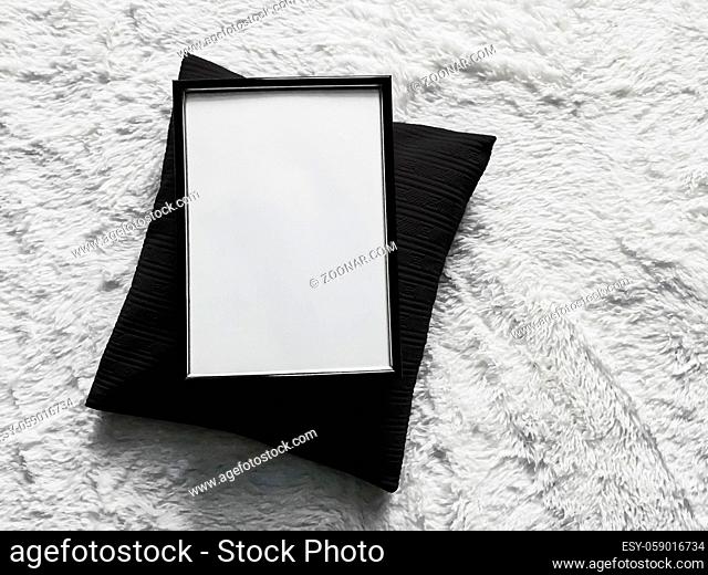 Thin wooden frame with blank copyspace as poster photo print mockup, black cushion pillow and fluffy white blanket, flat lay background and art product