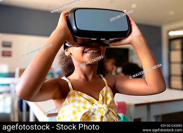 Close-up smiling african american elementary schoolgirl wearing vr glasses in classroom