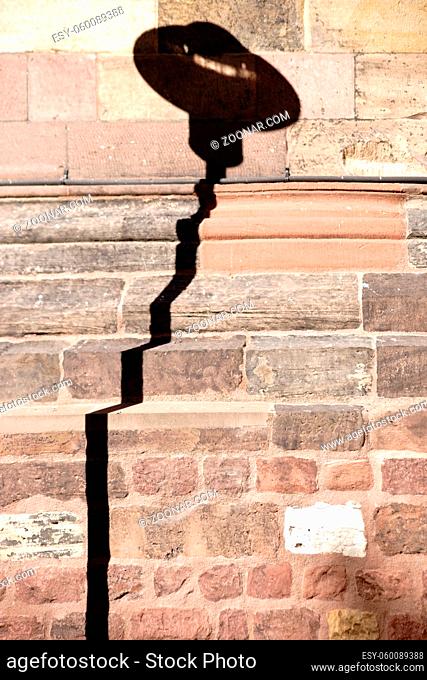 Ein markanter Laternenschatten auf einer gemauerten Wand einer Kirche