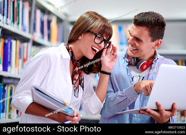 Two students using modern technology stand in the school library