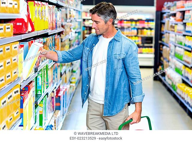 Handsome father picking box of cereals at supermarket