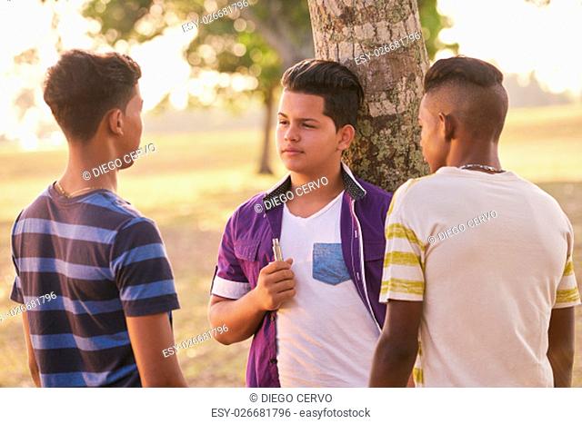 Youth culture, young people, group of male friends, multi-ethnic teens outdoors, multiracial boys together in park. Kids smoking electronic cigarette