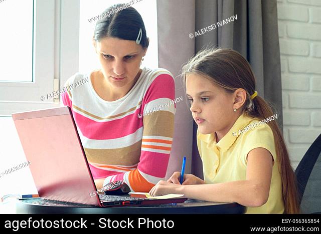 Mom and daughter solve homework using online distance learning