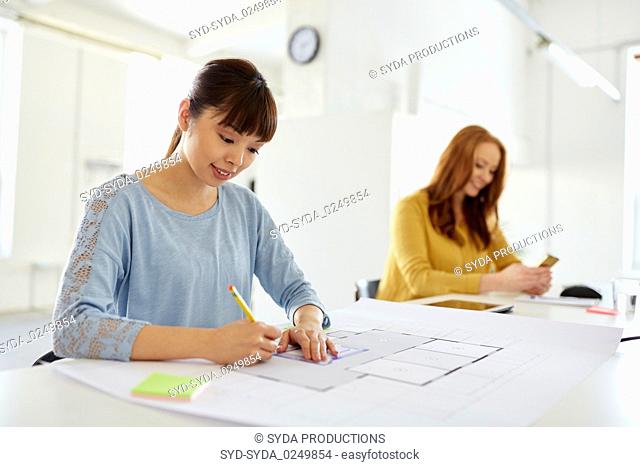 female architect with blueprint working at office