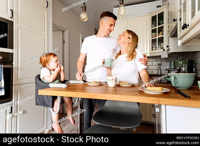Happy family with baby daughter at kitchen table