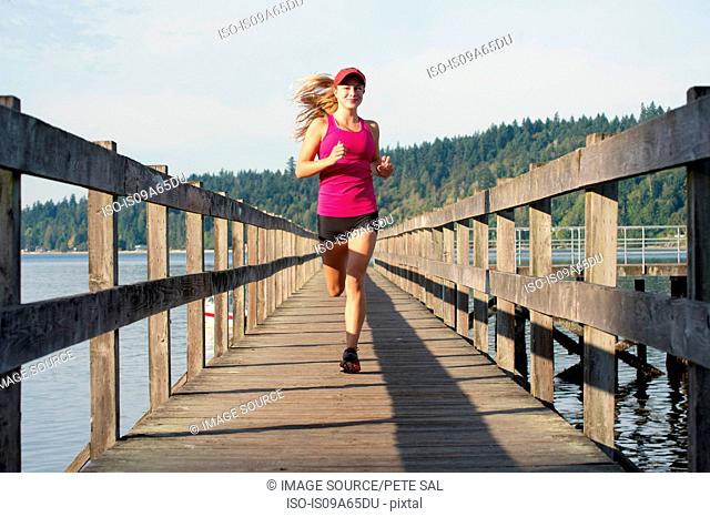 Teenage girl running on wooden dock