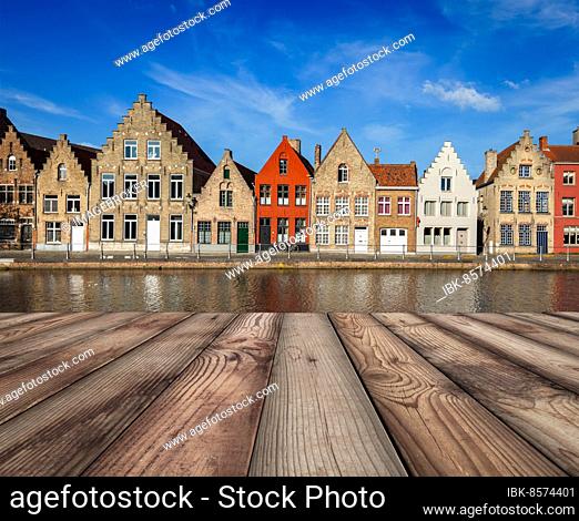 Wooden planks table with typical European Europe cityscape view, canal and medieval houses in background. Brugge, Belgium, Europe