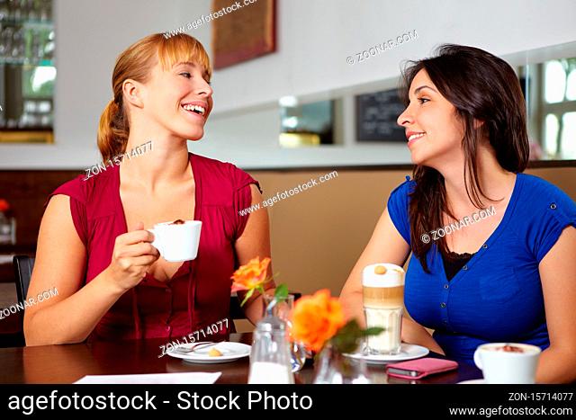 Zwei lachende Frauen mit Kaffee im Café