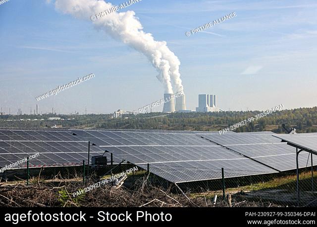 27 September 2023, Saxony, Groitzsch: Photovoltaic systems stand against the backdrop of the Lippendorf lignite-fired power plant in the open pit