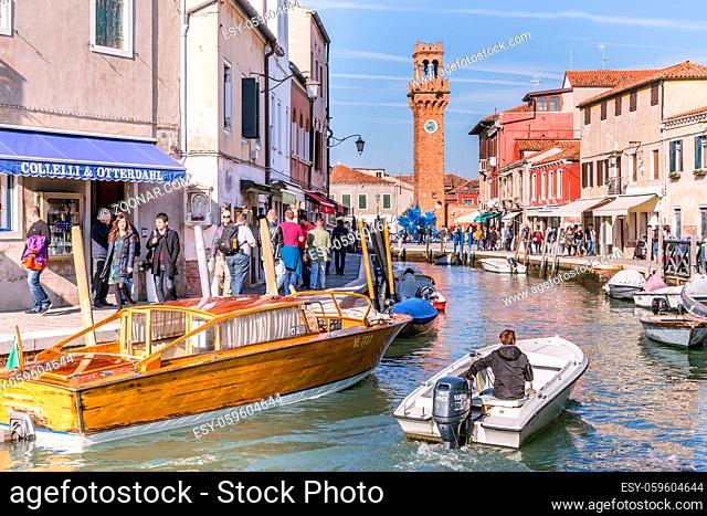 Murano Venice, Italy - October 29, 2016: View of the central canal and clock tower on Murano island in Venice Italy. The canal is surrounded with tourist shops...