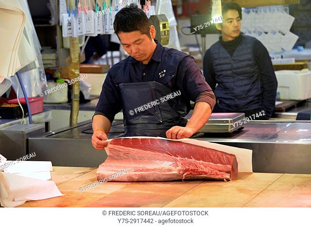 Japanese fishmonger slicing fresh tuna in Tsukiji market in early morning, Tokyo, Japan, Asia