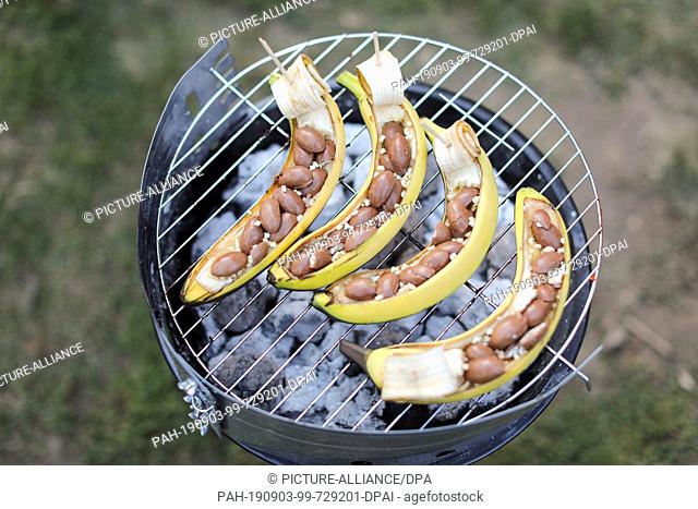 23 August 2019, Saxony, Leipzig: Bananas with chocolate sweets lie on a grill in a park in Leipzig during a barbecue party