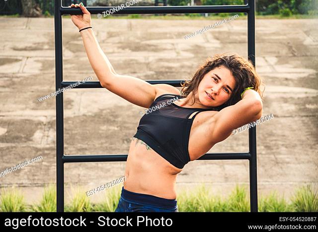 Attractive fit young woman in sport wear rest on the street workout area. The healthy lifestyle in the city. Street portrait strong woman poses at gym