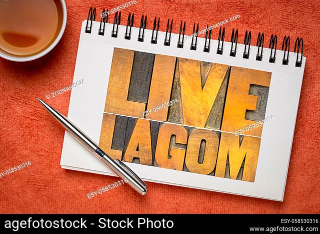 live lagom word abstract in vintage letterpress wood type in a sketchbook with a cup of tea, Swedish balanced lifestyle and moderation concept
