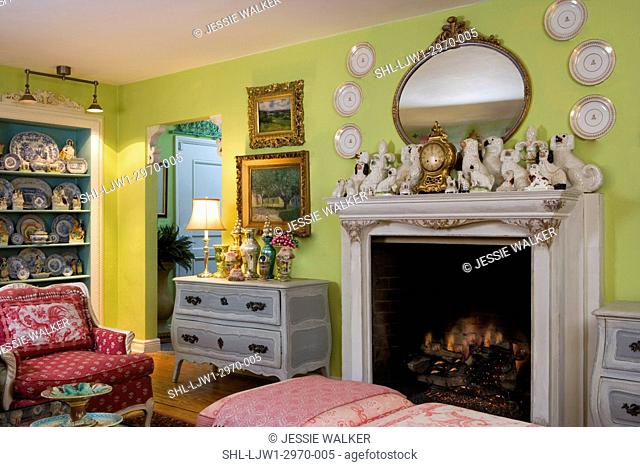 LIVING ROOMS: Bright green walls with bright raspberry accent colors, collection displays of plates over fireplace, chelses dog porcelain figures on mantel