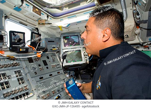 Astronaut Jose Hernandez, STS-128 mission specialist, uses a communication system on the aft flight deck of Space Shuttle Discovery while docked with the...