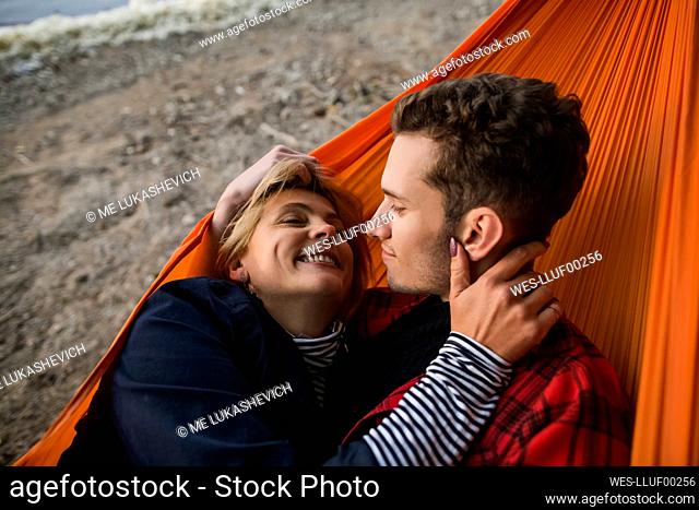 Happy girlfriend relaxing with boyfriend in hammock