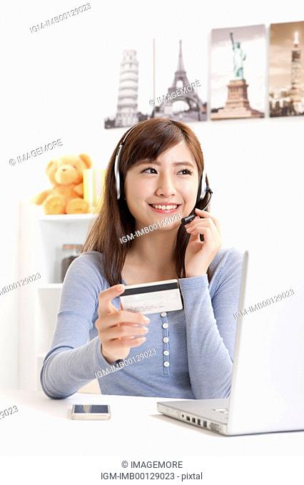 Young woman holding credit card and wearing headphones with smile