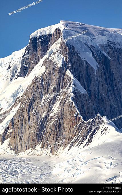 Beautiful mountain peak made of rock covered with vertical ridges and glaciers