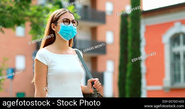 Portrait of young woman walking in city street wearing protective mask