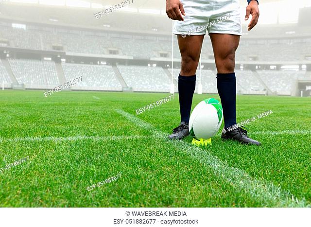 African American male rugby player standing near rugby ball in stadium
