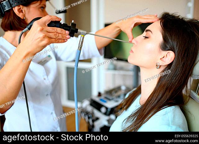 Female laryngologist and patient in chair, exam. Nose examination in clinic, professional diagnostic, ent doctor. Medical specialist and woman in hospital