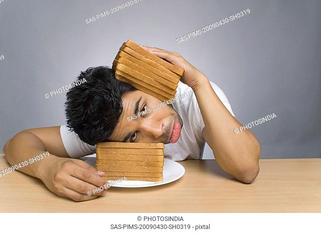 Man looking sad and putting his head between the slices of bread