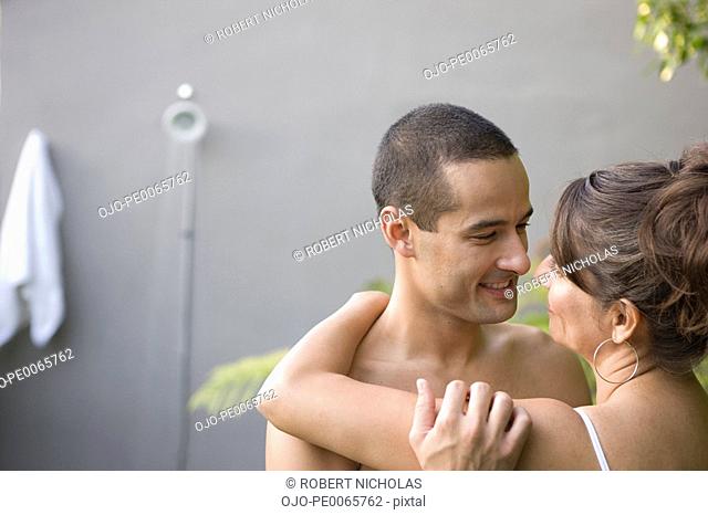 Couple hugging by outdoor shower