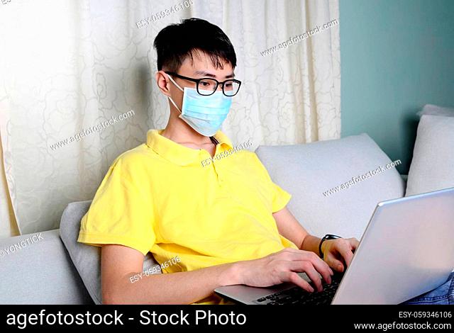 An asian man is working from home during pandemic coronavirus Covid-19. Ccoronavirus covid 19 infected patient in quarantine room using computer....