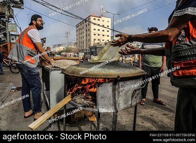 08 November 2023, Palestinian Territories, Rafah: A Palestinian baker uses firewood to bake traditional Saj bread due to the lack of cooking gas as the result...