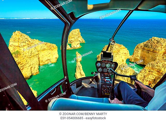 Helicopter cockpit interior flying on scenic landscape of boat trip between cliffs and natural rock formations of Ponta da Piedade